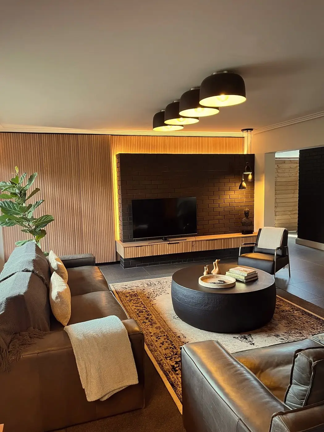 Media room with reeded timber wall, dark sofas, black coffee table