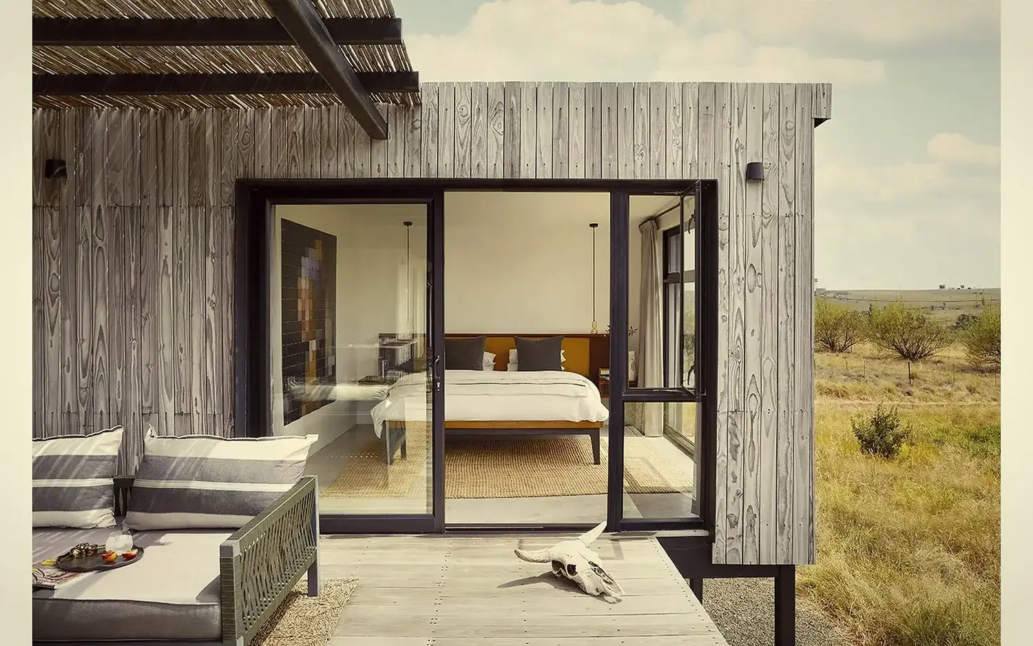 Bedroom from the deck · weathered cladding, sliding doors, koppies beyond